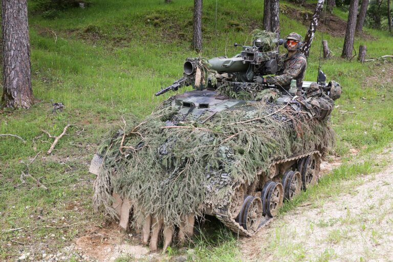 Deutscher Bundeswehr-Soldat auf getarntem Schützenpanzer im Wald