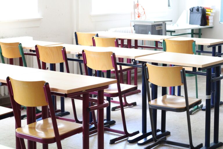 Heller leerer Klassenraum mit Holzstühlen und Tischen