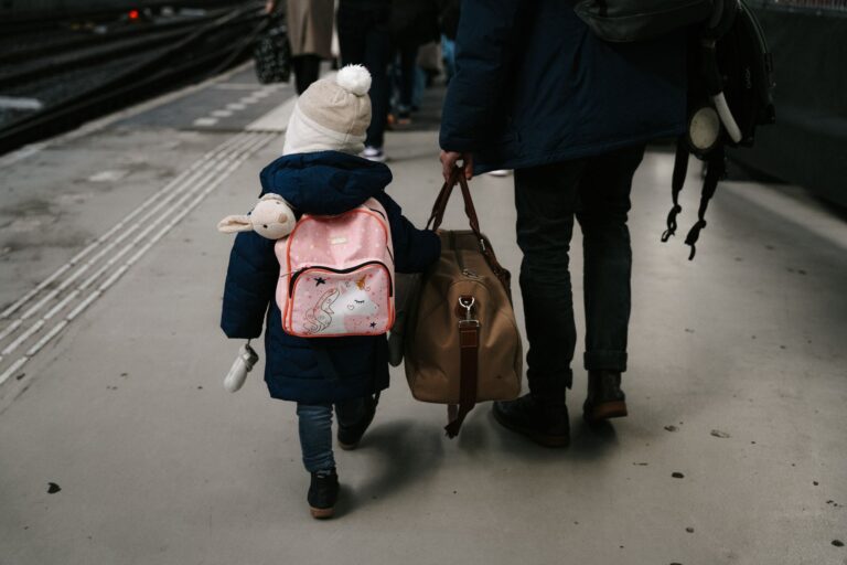 Kind und Erwachsener mit Taschen am Bahnsteig in Amsterdam