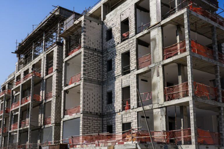 Moderner mehrstöckiger Wohnungsbau im Rohbau mit Gerüst und Sicherheitsnetzen