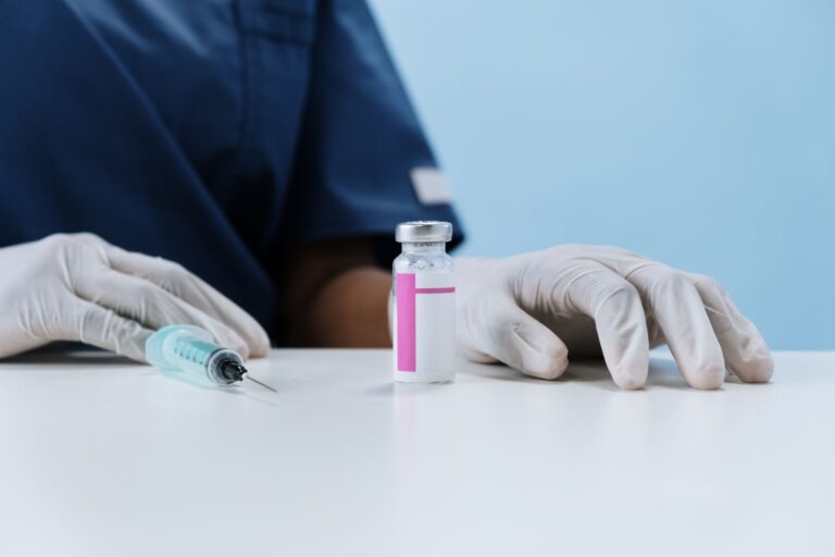 Nahaufnahme von medizinischem Personal mit Spritze und Impfstofffläschchen