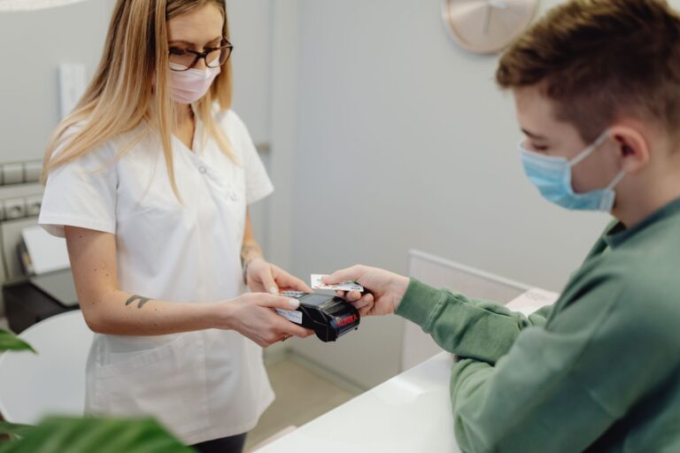 Gesundheitsfachkraft hält Kartenlesegerät, Patient zahlt mit Karte
