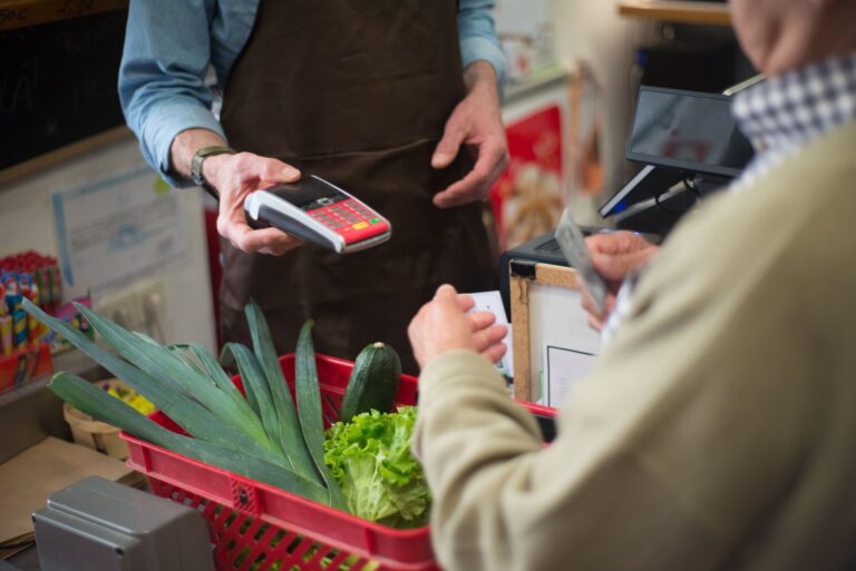 Nahaufnahme eines Kunden, der an der Kasse mit Gemüse bezahlt